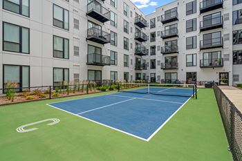 an outdoor tennis court in front of an apartment building